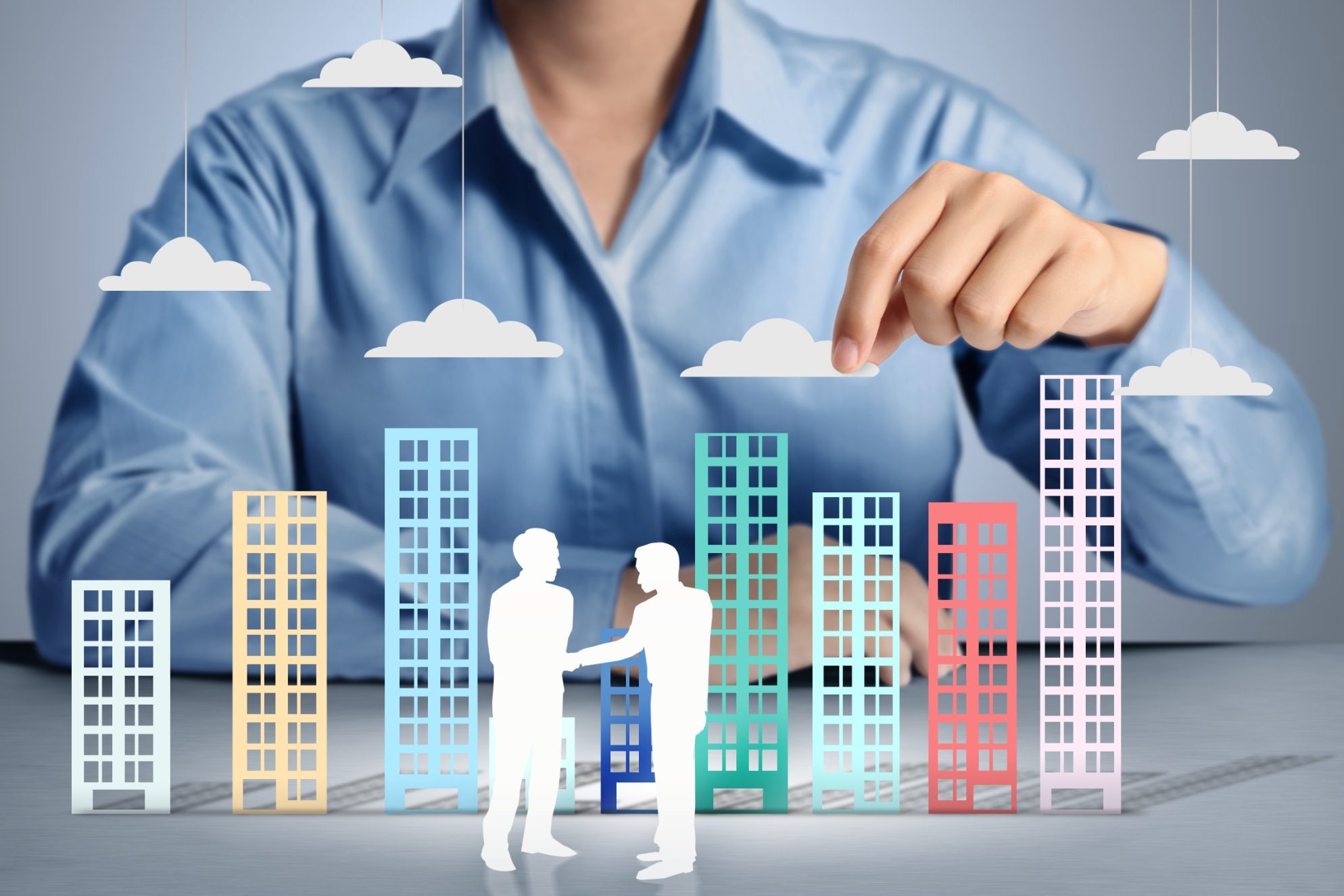 Business people shaking hands with graphic city buildings and clouds in the background.