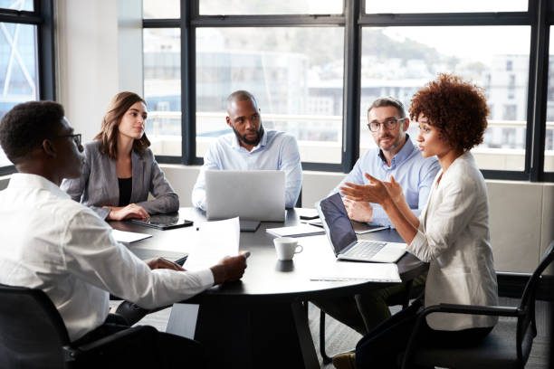 A diverse group of professionals engaged in a discussion around a conference table.